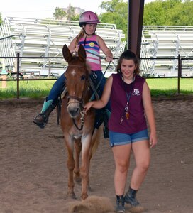 Olivia Byers rides a horse led by Sofia Perez-Gomez during the Joint Base San Antonio Exceptional Family Member Program Equestrian Camp, held at the JBSA-Fort Sam Houston Equestrian Center June 25-27. Byers was one of 12 children who participated in the camp, which allowed special needs children from military families and their siblings to learn about horsemanship and to ride horses. Perez-Gomez served as a camp volunteer.