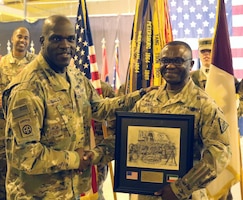 Command Sgt. Maj. Bernard Small, 1st Theater Sustainment Command, presents Command Sgt. Maj. Ekondua Amoke, 8th Medical Brigade, with a plaque before a transfer of authority ceremony between 8th Medical Brigade and 3d Medical Command Deployment Support - Forward at Camp As Sayliyah, Qatar, July 18, 2019.