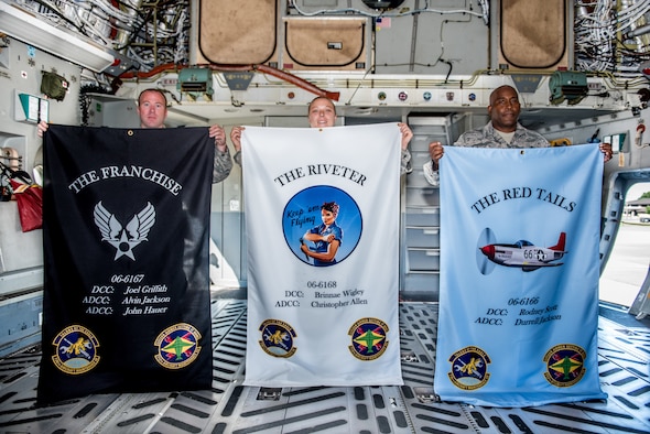 Tech. Sgt. Joel Griffith and Master Sgts. Brinnae Wigley and Rodney Scott, 712th Aircraft Maintenance Squadron crew chiefs, hold personal flags during a dedicated crew chief ceremony at Dover Air Force Base, Delaware, July 13, 2019. The flags were awarded to the three crew chiefs for their job performance and diligent service. (U.S. Air Force photo by Staff Sgt. Damien Taylor)