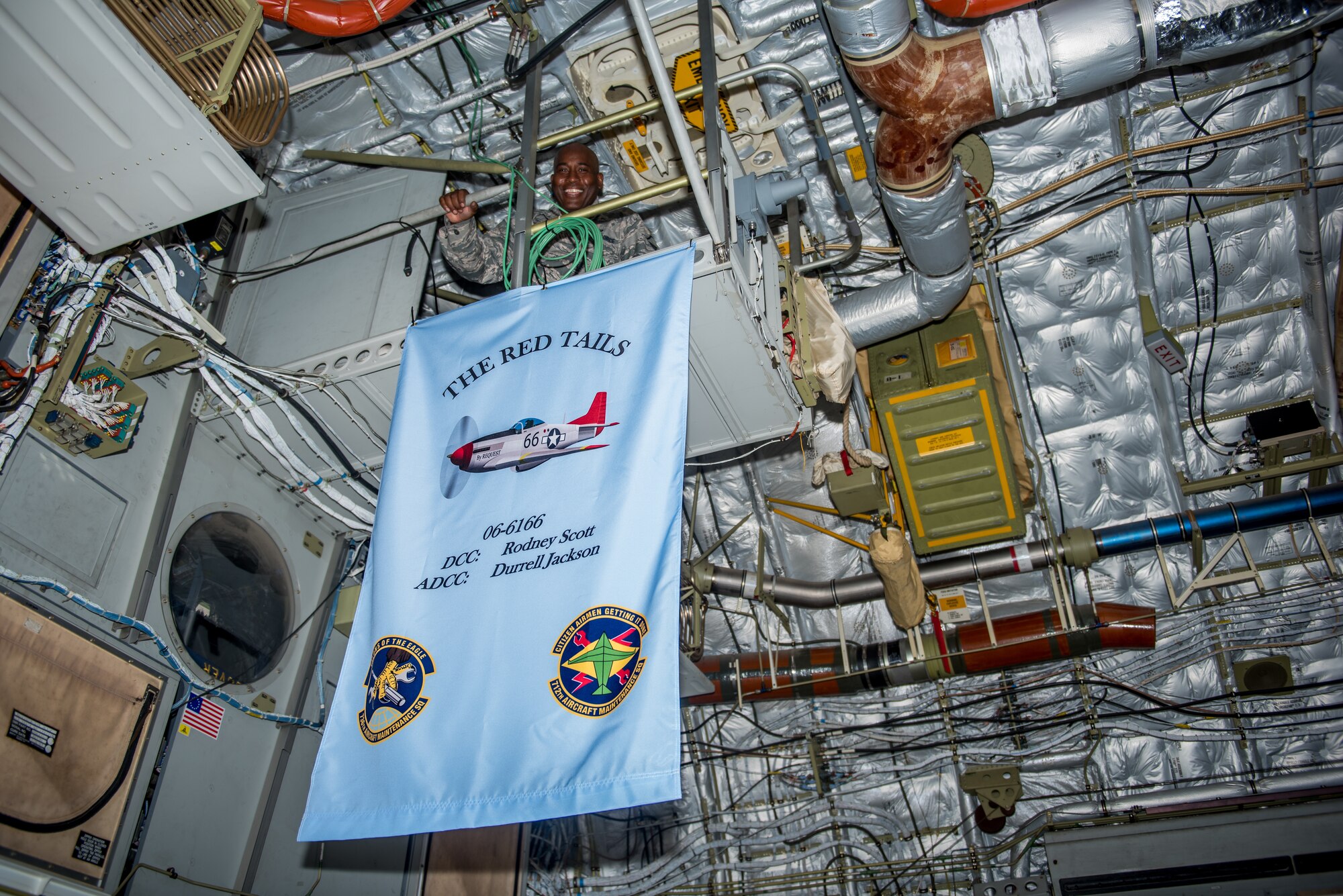 Master Sgt. Rodney Scott, 712th Aircraft Maintenance Squadron crew chief, hangs a personal flag from a C-17 Globemaster III catwalk during a dedicated crew chief ceremony at Dover Air Force Base, Delaware, July 13, 2019. Scott has been the DCC for the C-17 serial number 06-6116 since 2009. (U.S. Air Force photo by Staff Sgt. Damien Taylor)