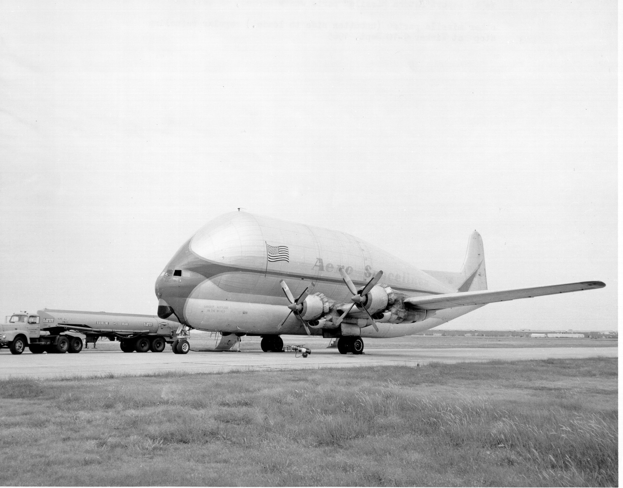 The Aero Spacelines Inc.’s B-377PG “Pregnant Guppy” shown at Tinker Air Force Base in the mid-1960s with well-worn markings as the aircraft provided outsized cargo transport in support of the Apollo program. Barely visible on the nose is the wording, “Largest Airplane In The World.” The C-97 variant was flown to NASA’s Dryden facility at Edwards Air Force Base for tests and evaluation by pilots Joe Vensel and Stan Butchart in October 1962. The outsized cargo aircraft incorporated the wings, engines, lower fuselage and tail from a Boeing 377 Stratocruiser with a huge upper fuselage more than 20 feet in diameter. The modified aircraft was built primarily to carry portions of the Saturn 5 rockets from the manufacturer to Cape Canaveral.