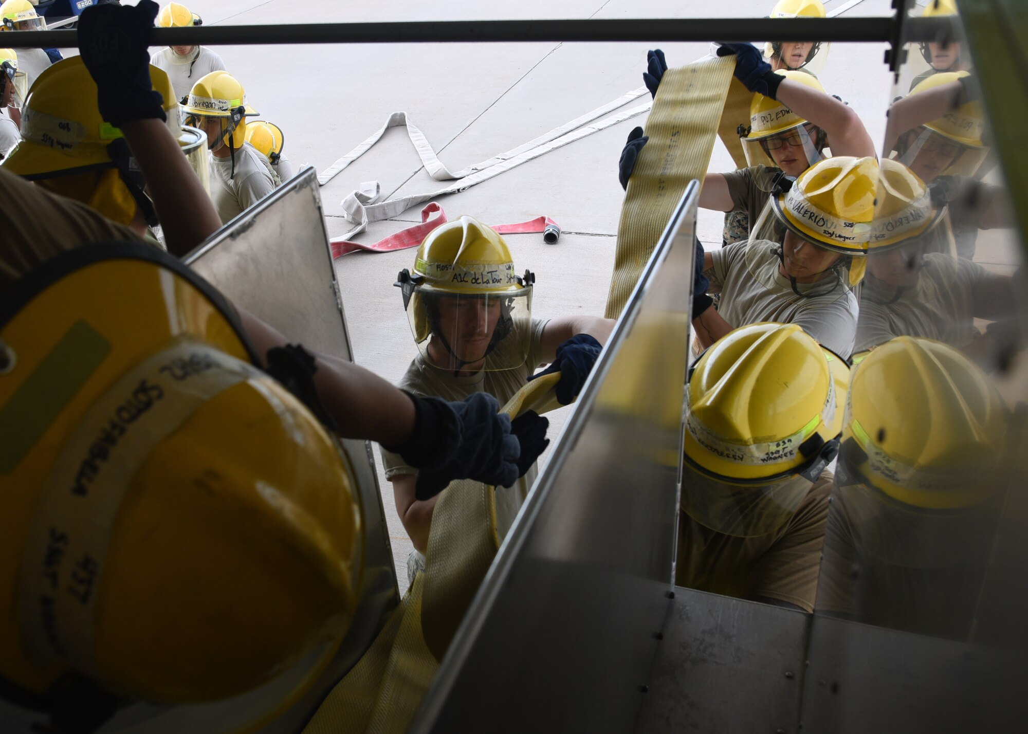 U.S. Military students from 312th Training Squadron practice unraveling fire hoses efficiently from the back of a fire truck outside the Louis F. Garland Department of Defense Fire Academy on Goodfellow Air Force Base, Texas, July 11, 2019. Students were trained in a stress-induced environment to practice valuable skills such as remaining calm, working in teams and effective communication, all of which are needed in real-life firefighting scenarios.  (U.S. Air Force Photo by Airman 1st Class Abbey Rieves/Released)