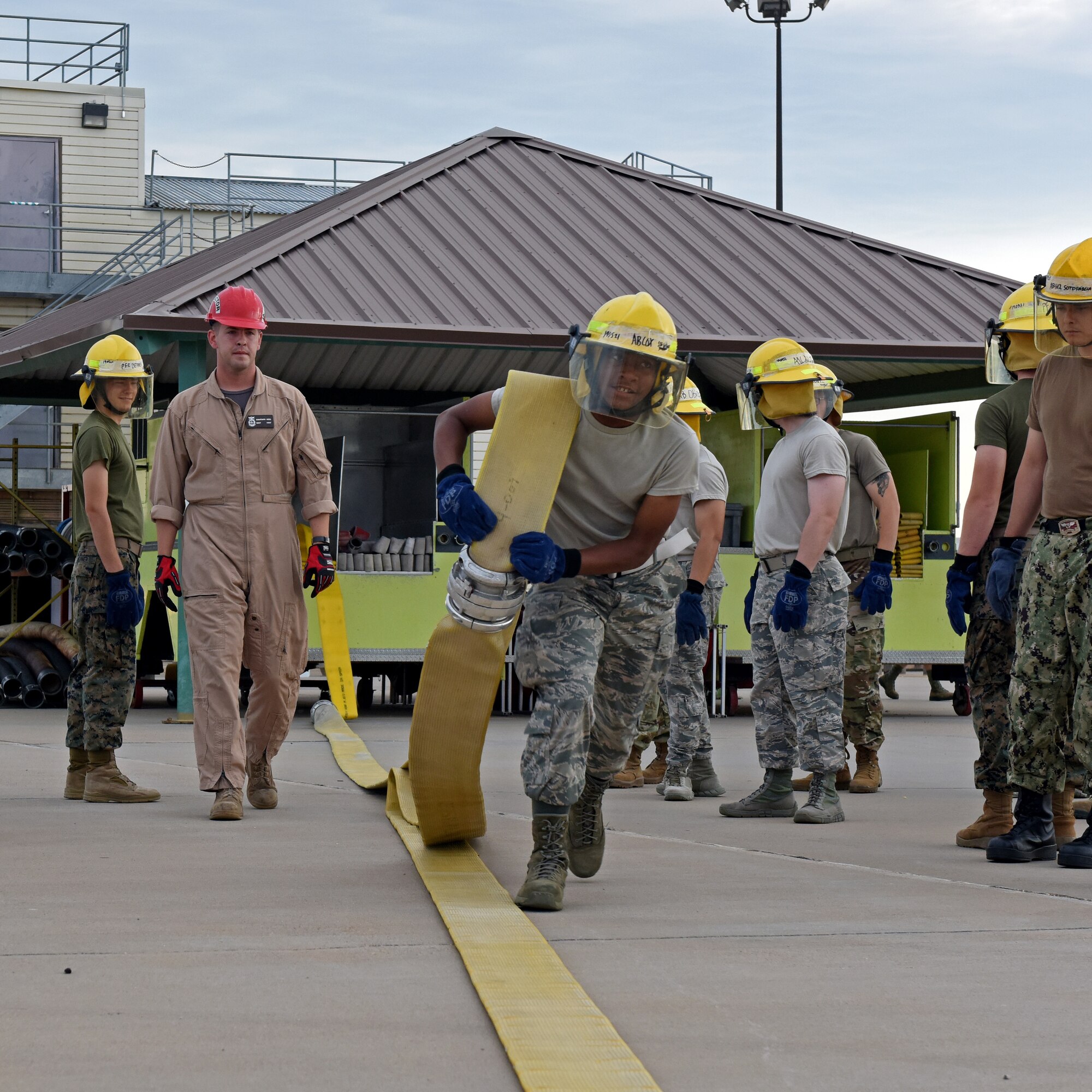 U.S. Military students from the 312th Training Squadron, in the firefighter training course, complete a drill in which they must run a fire hose out 100 meters at the Louis F. Garland Department of Defense Fire Academy on Goodfellow Air Force Base, Texas, July 11, 2019. The students complete drills such as this to build strength and endurance to complete their duties. (U.S. Air Force photo by Airman 1st Class Robyn Hunsinger/Released)