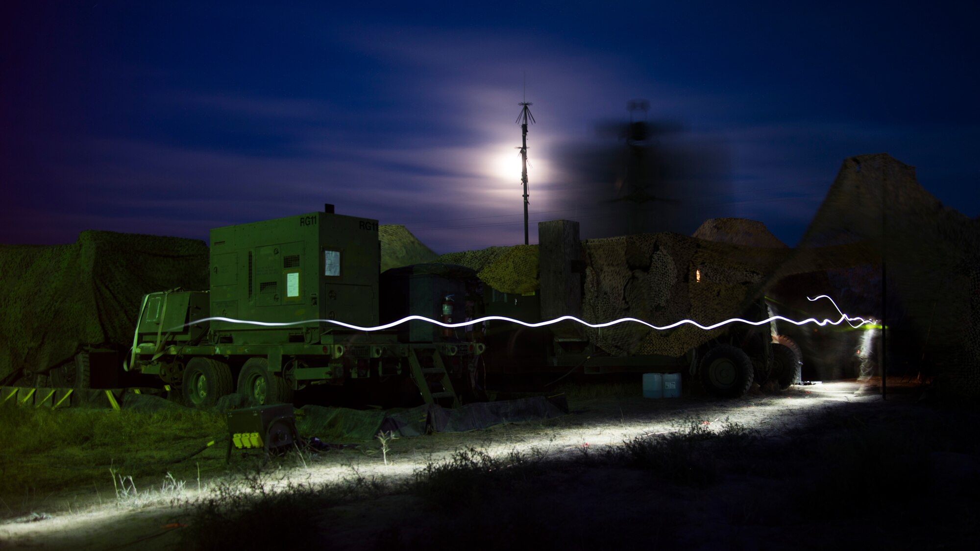 A U.S. Air Force Airman from the 726th Air Control Squadron walks by a spinning TPS-75 radar sytem with a flashlight in hand during Hardrock Exercise 19-2, July 15, 2019, at Mountain Home Air Base, Idaho. The exercise was in a simulated deployed location where the base was built from the ground up and took control of the airspace. (U.S. Air Force photo by Airman 1st Class Andrew Kobialka)