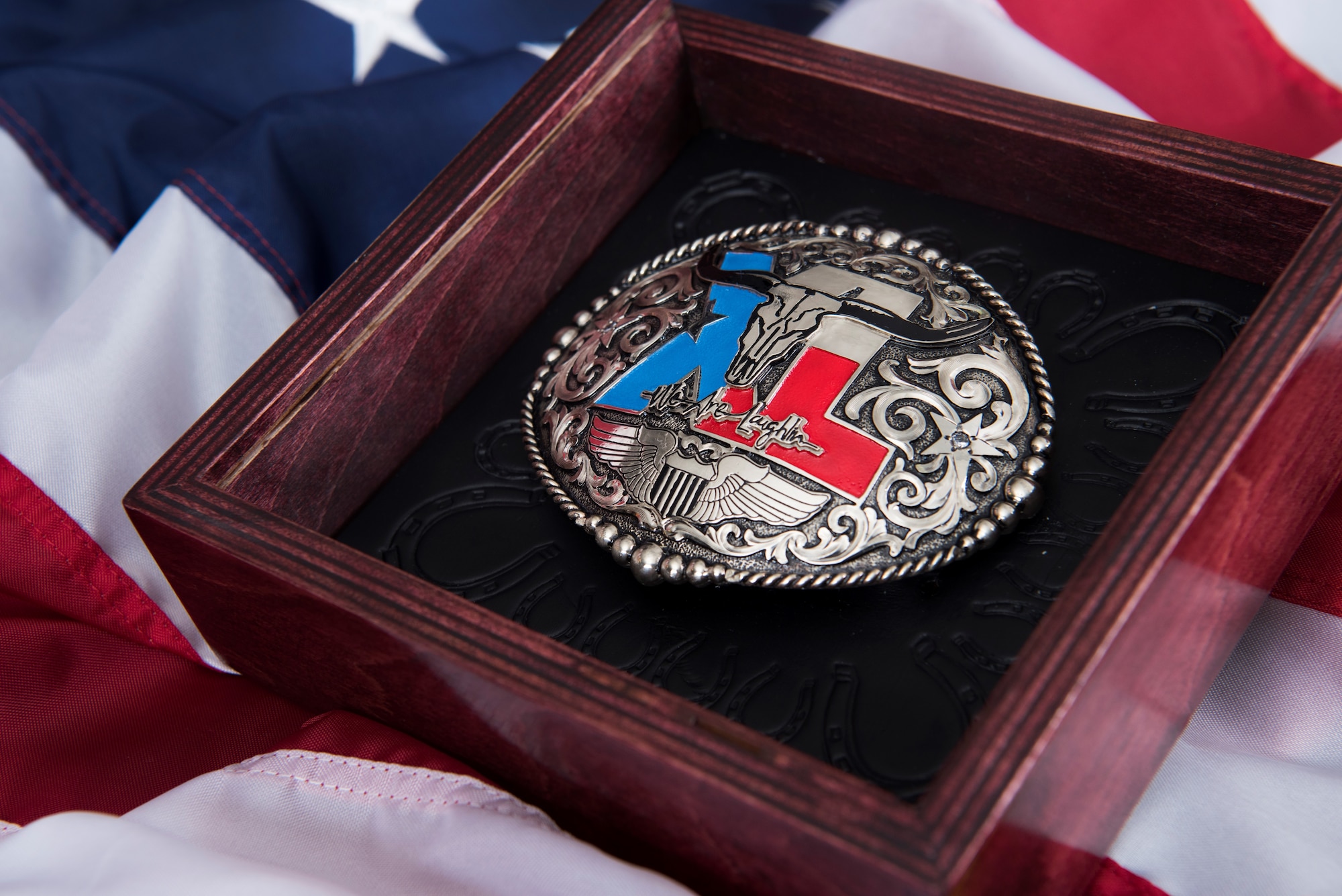 A custom belt buckle, designed for the wing’s newly inducted lifetime Honorary Commander lays in its shadow box at Laughlin Air Force Base, Texas, July 17, 2019. Nominations for this elite lifetime program, formally known as Laughlin’s Wings of Amistad, are not guaranteed during each commander’s tenure; however, each nominee exhibits a lifetime impact on this base community. (U.S. Air Force photo by Airman 1st Class Marco A. Gomez)