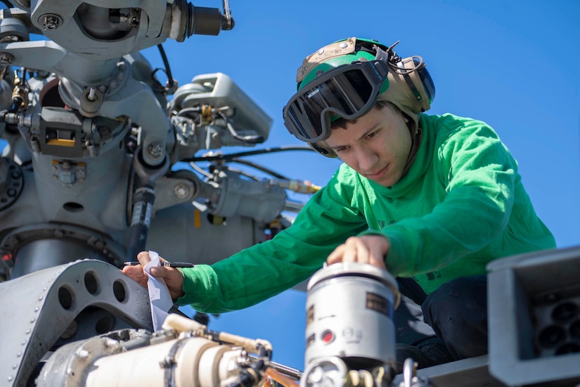 A sailor works with equipment.