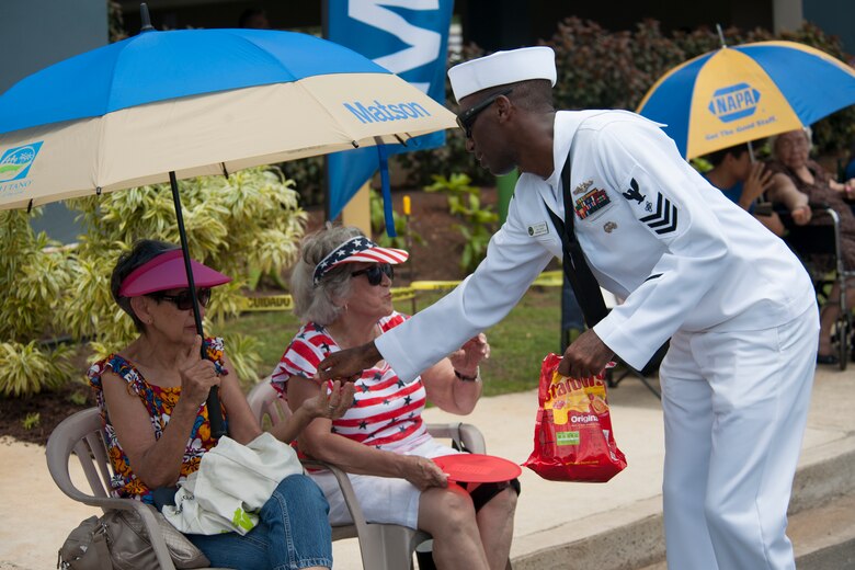 190721-N-AY639-0010 AGANA, Guam (July 21, 2019) Electronics Technician (Navigation) 1st Class Alex Hepburn, a native of West Palm Beach, Fla., hands out candy to parade attendees during the annual Guam Liberation Day Parade, July 21. The celebration commemorates the 75th anniversary of the liberation of Guam from Japanese occupation by U.S. forces during World War II.