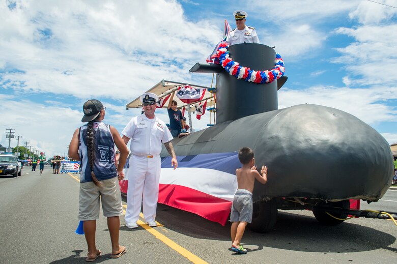AGANA, Guam (July 21, 2019) Capt. Timothy Poe, Commander, Submarine Squadron Fifteen, and Master Chief Machinist's Mate (Nuclear) Jason Hays, assigned to CSS-15, greet children during the annual Liberation Day parade. The celebration commemorates the 75th anniversary of the liberation of Guam from Japanese occupation by U.S. forces during World War II.