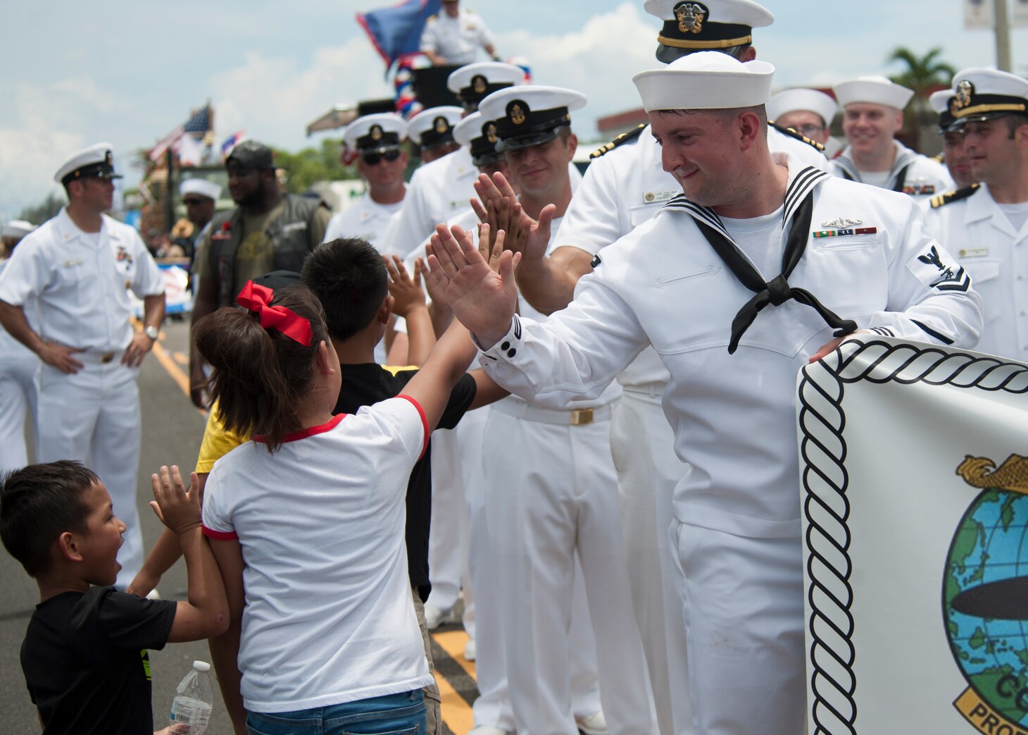 190721-N-AY639-0007 AGANA, Guam (July 21, 2019) Fire Control Technician 2nd Class Patrick Trevino high-fives children during the annual Guam Liberation Day Parade, July 21. The celebration commemorates the 75th anniversary of the liberation of Guam from Japanese occupation by U.S. forces during World War II.