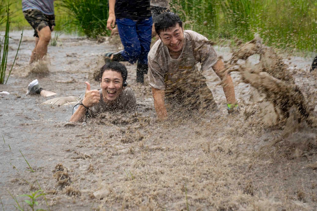 泥水の中ではしゃぐ日本人参加者。キャンプ富士で７月21日、約400人の地元及び米軍関係者が参加した約６キロの障害物レースが開催され、それぞれが楽しみながらコースを完走していました。