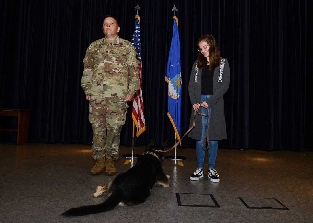 U.S. Air Force Lt. Col. Jesse Goens, 31st Security Forces Squadron commander, and Megan Lasica stand with Military Working Dog Cigan during a retirement ceremony at Aviano Air Base, Italy, July 19, 2019. MWD Cigan received an Air Force Achievement Medal for his work since 2015 at Aviano AB. (U.S. Air Force photo by Staff Sgt. Rebeccah Woodrow)