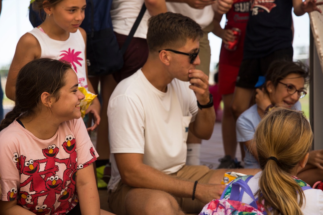 A U.S. Marine with Special Purpose Marine Air-Ground Task Force Crisis Response-Africa 19.2, Marine Forces Europe and Africa, eats lunch with students from La Inmaculada charter school during a community relations event on Moron Air Base, Spain, July 2, 2019. Marines and Sailors of SPMAGTF-CR-AF played various American games with the students such as cornhole, football, and baseball while speaking English to help increase the students’ fluency in the language. Community relations events like this help strengthen relationships between the local communities and the deployed Marines. SPMAGTF-CR-AF is deployed to conduct crisis-response and theater-security cooperation operations in Africa and promote regional stability by conducting military-to-military training exercises throughout Europe and Africa. (U.S. Marine Corps photo by Cpl. Margaret Gale)