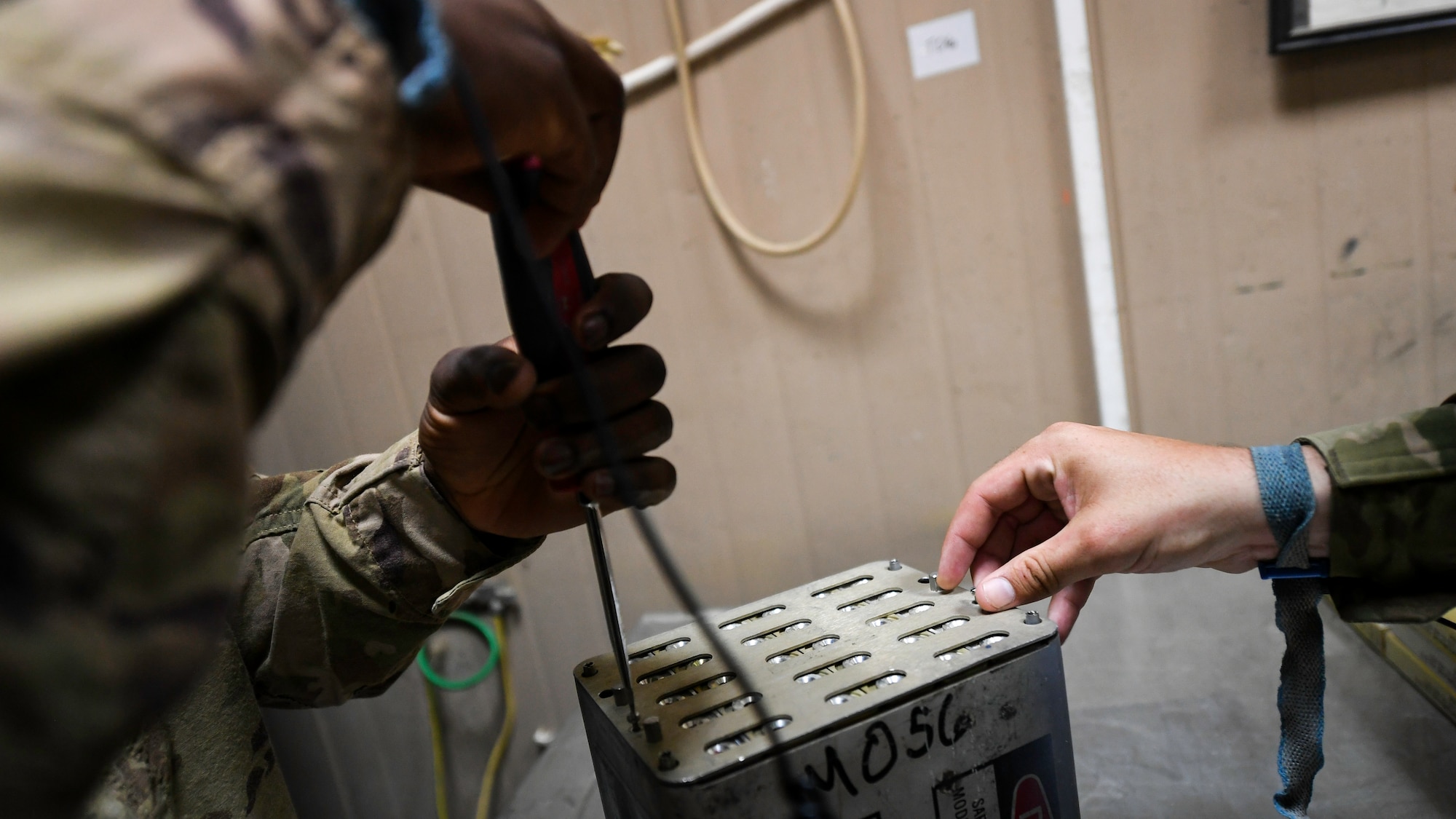 U.S. Air Force Airman 1st Class Conner Quintana and Senior Airman Samson Lawanson, 386th Expeditionary Maintenance Squadron munitions technician journeymen, install a security plate onto a flare housing module at Ali Al Salem Air Base, Kuwait, July 18, 2019. Security plates are used for keeping flare and chaff units in place and to assist in identifying what countermeasure package is currently installed. (U.S. Air Force photo by Staff. Sgt. Mozer O. Da Cunha)