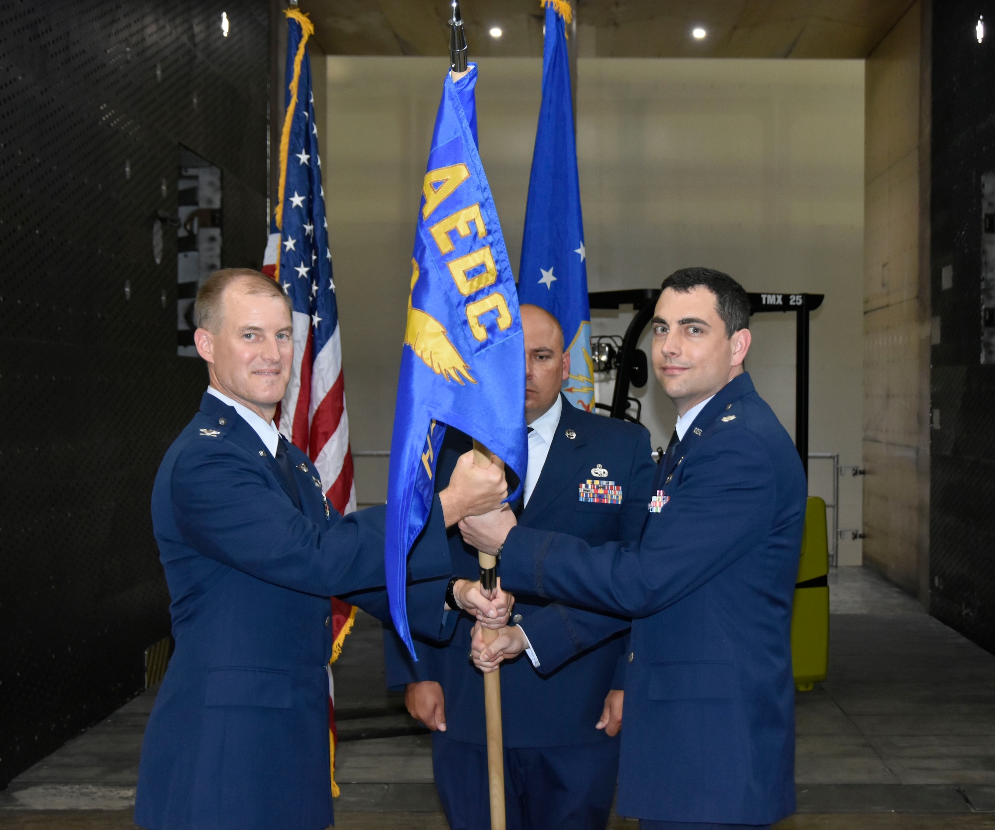 Incoming AEDC Flight Systems Combined Test Force Director Lt. Col. John McShane, right, accepts the Flight Systems CTF guidon from AEDC Test Operations Division Chief Col. Keith Roessig during a June 28 Change of Leadership ceremony in the Propulsion Wind Tunnel Model Installation Building at Arnold Air Force Base. McShane comes to Arnold from Washington, D.C., where he most recently served as a Program Element Monitor for Advanced Aircraft Technology at the Directorate of Special Programs, Assistant Secretary of the Air Force (Acquisition, Technology & Logistics), at the Pentagon. (U.S. Air Force photo by Bradley Hicks)