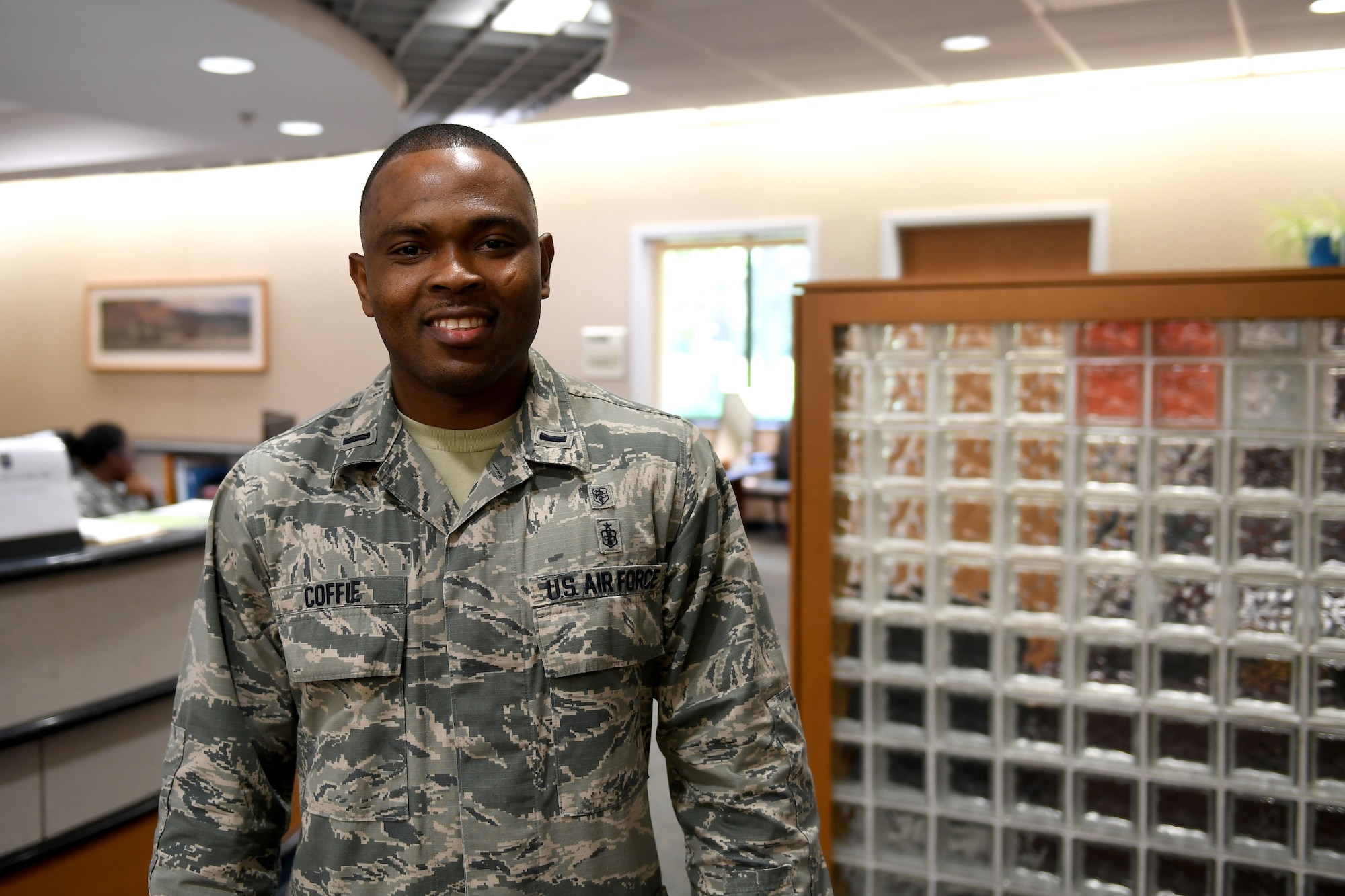 A man in the Airman Battle Uniform smiles at the camera.