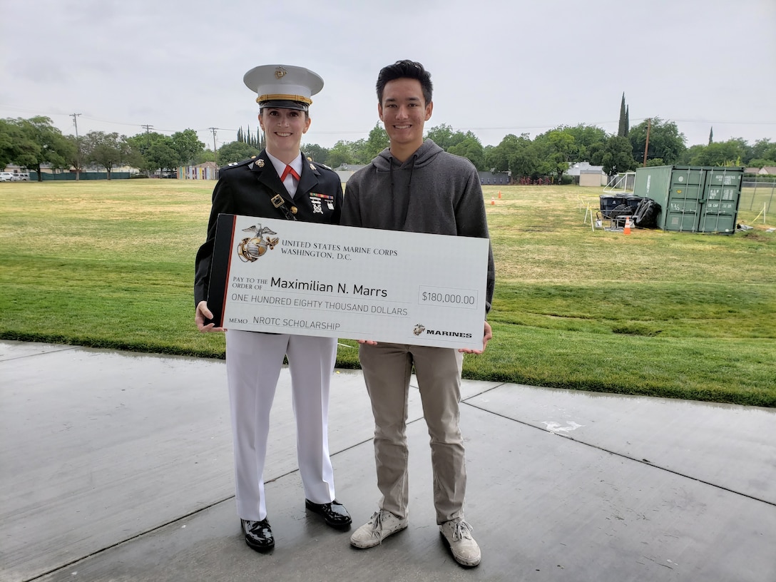 U.S. Marine Capt. Rachel Baker presents Maximilian Mars with his NROTC scholarship check. Mars was one of eight students from Recruiting Station Sacramento to be selected to receive the scholarship.