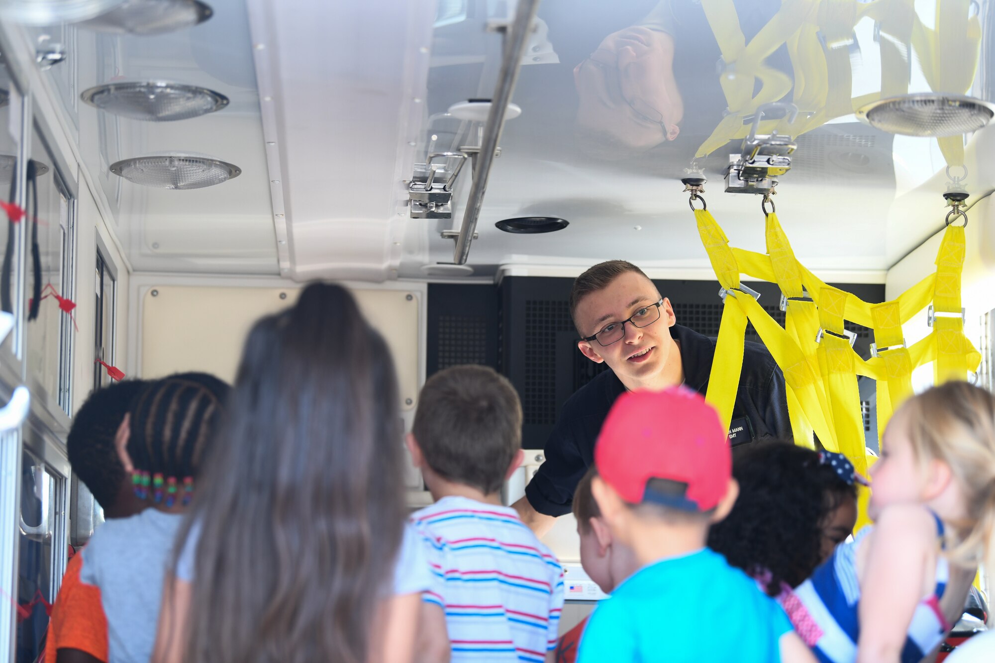 A 48th Medical Group emergency response technician shows children around an ambulance during an interactive vehicle display at Royal Air Force Lakenheath, England, July 3, 2019. The event was hosted by the 48th Logistics Readiness squadron and also included a wrecker recovery vehicle, an all-terrain forklift, patrol vehicle, an ATV and a Humvee. (U.S. Air Force photo by Airman 1st Class Shanice Williams-Jones)