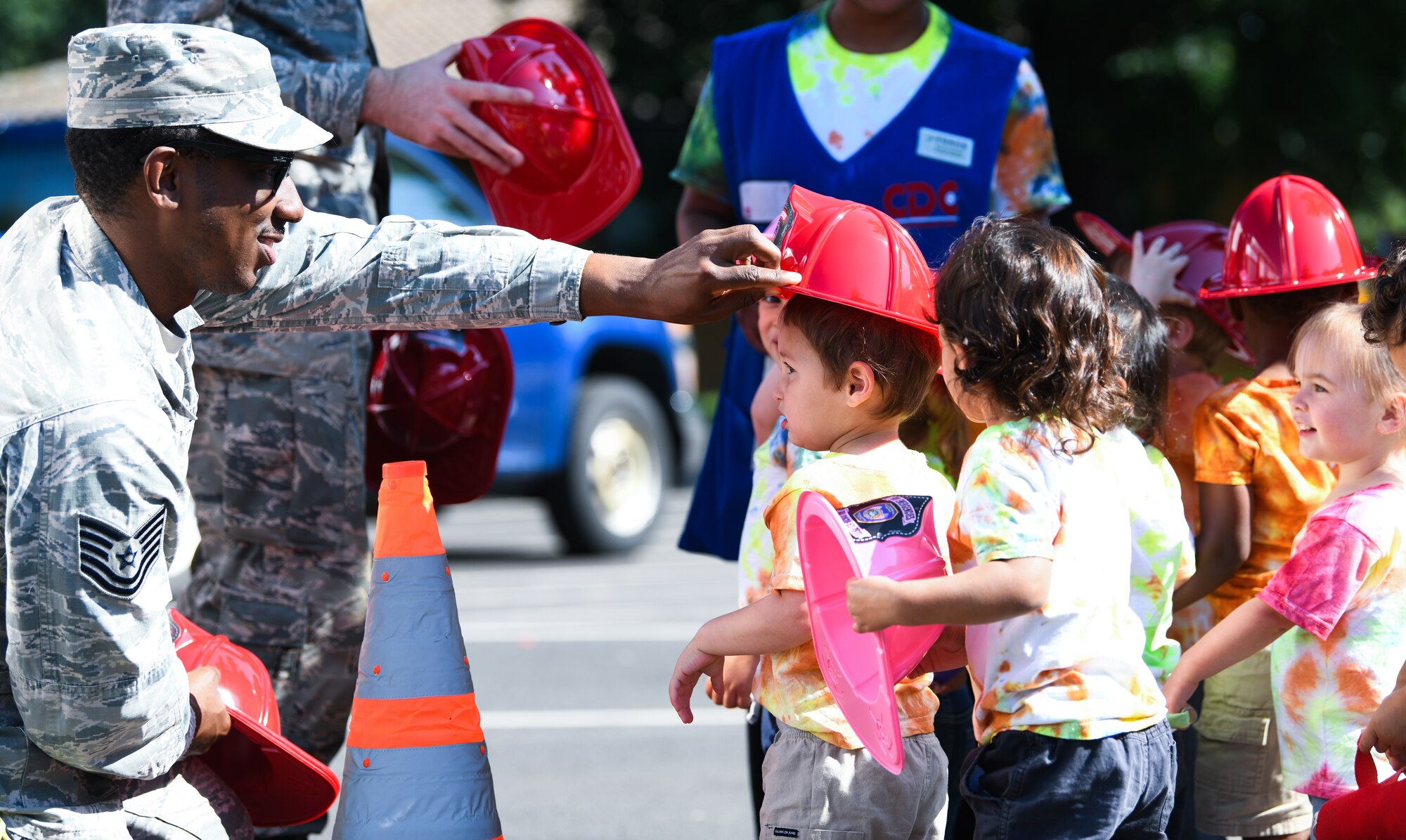 A 48th Civil Engineer Squadron firefighter places a hat atop a child’s head during an interactive vehicle display at Royal Air Force Lakenheath, England, July 3, 2019. The event was hosted by the 48th Logistics Readiness squadron, allowing the children to interact with the Airmen who work in transportation and contribute to the nation’s safety and defense. (U.S. Air Force photo by Airman 1st Class Shanice Williams-Jones)