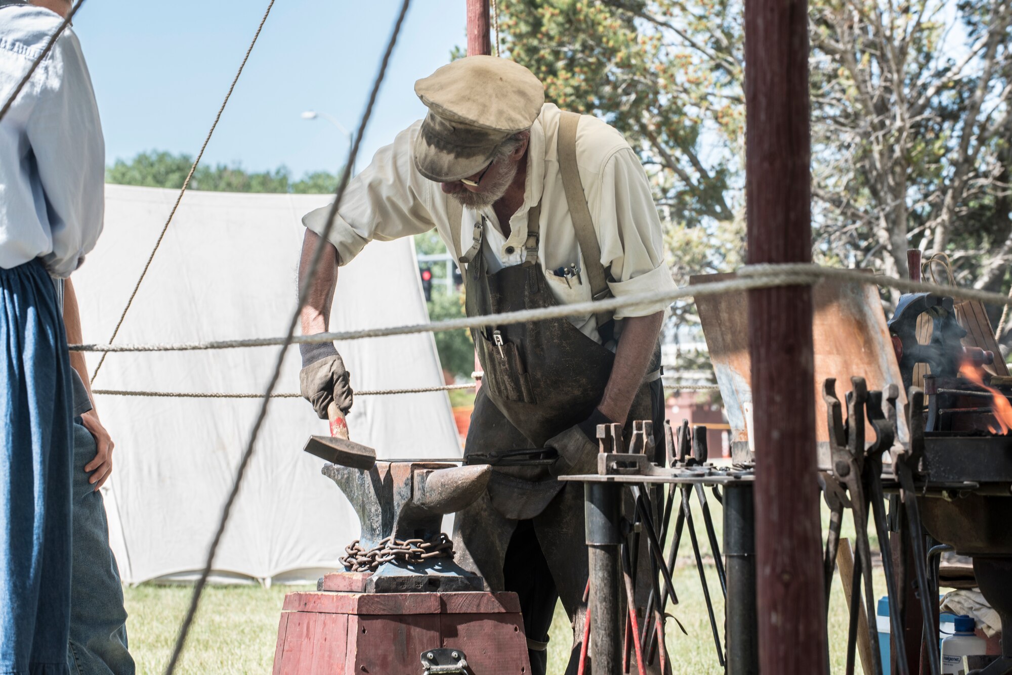 Jan Manning, Fort DA Russell Days volunteer, hammers an 'S' hook into iron for a blacksmith demonstration at F.E. Warren Air Force Base, Wyo., July 19, 2019. These presentations allow visitors to feel like they’re taking a trip back to the early days of the base. The annual open house invites the community and visitors to tour the base to learn about its history and its current ICBM deterrence mission. (U.S. Air Force photo by Senior Airman Abbigayle Williams)