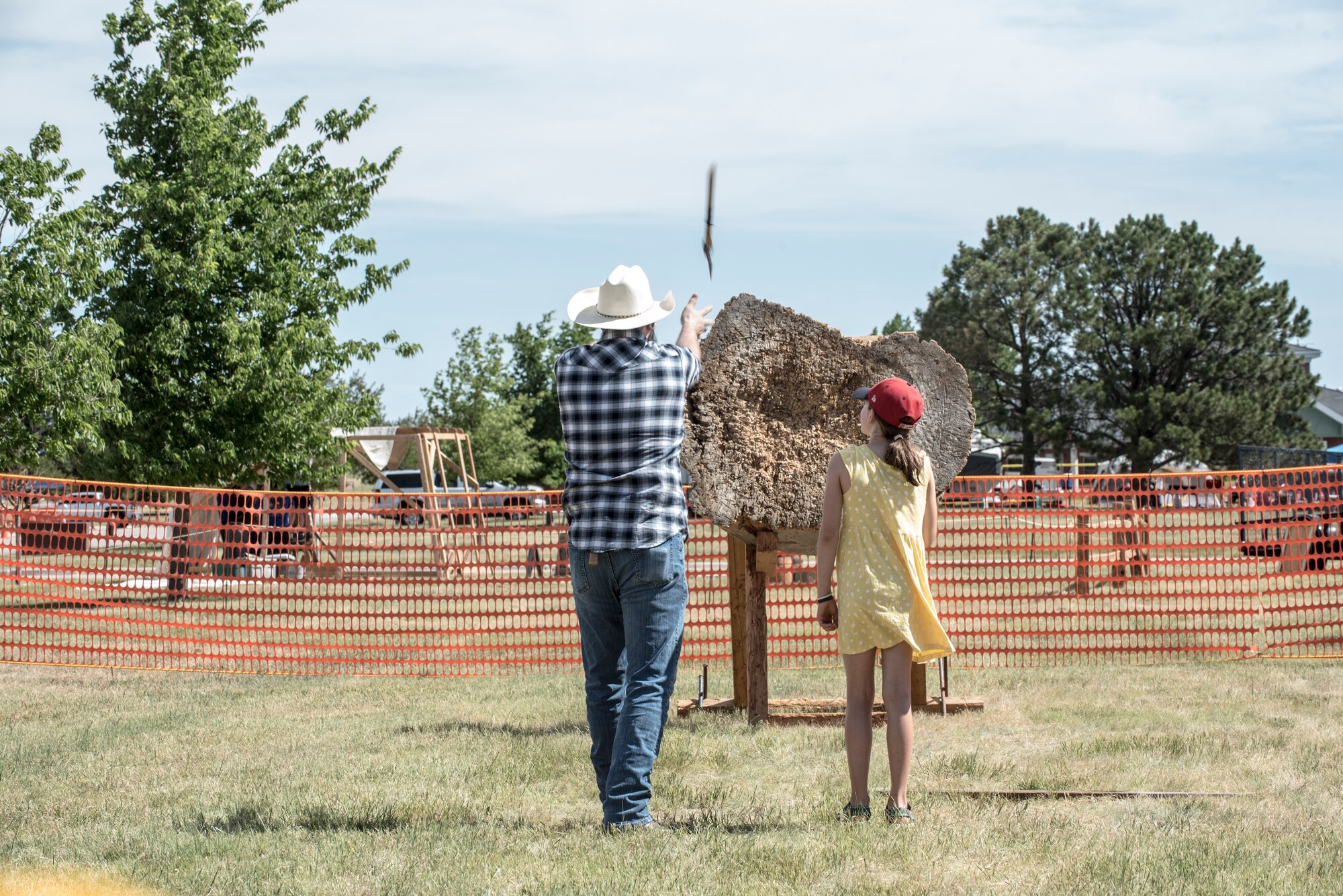 An ax thrower demonstrates proper technique to a visitor during Fort D.A. Russell Days, July 19, 2019, on F.E. Warren Air Force Base, Wyo. The annual open house invites the community and visitors to tour the base to learn about its history and its current ICBM deterrence mission. (U.S. Air Force photo by Senior Airman Abbigayle Williams)