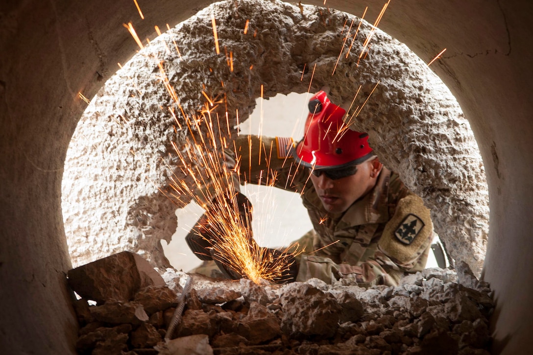 A soldier uses equipment to break through concrete.