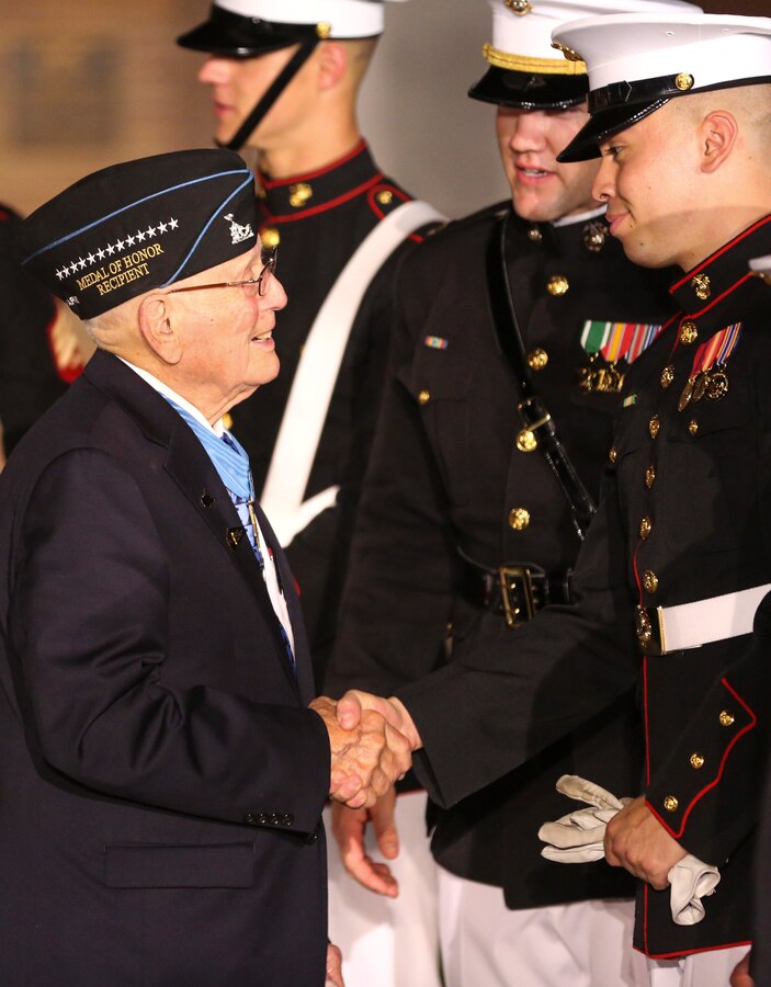 Corporal Jose Soto, number two rifle inspector, U.S. Marine Silent Drill Platoon, shakes hands with retired CWO4 and Medal of Honor recipient Hershel “Woody” Williams after at Friday Evening Parade at Marine Barracks Washington D.C., July 19, 2019. Medal of Honor recipient and retired CWO4 Hershel “Woody” Williams was the guest of honor for the evening and Lt. Gen. Charles G. Chiarotti, deputy commandant, Installations and Logistics, was the hosting official.