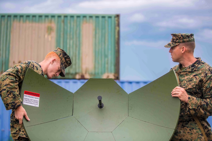 Two Marines work on a satellite.