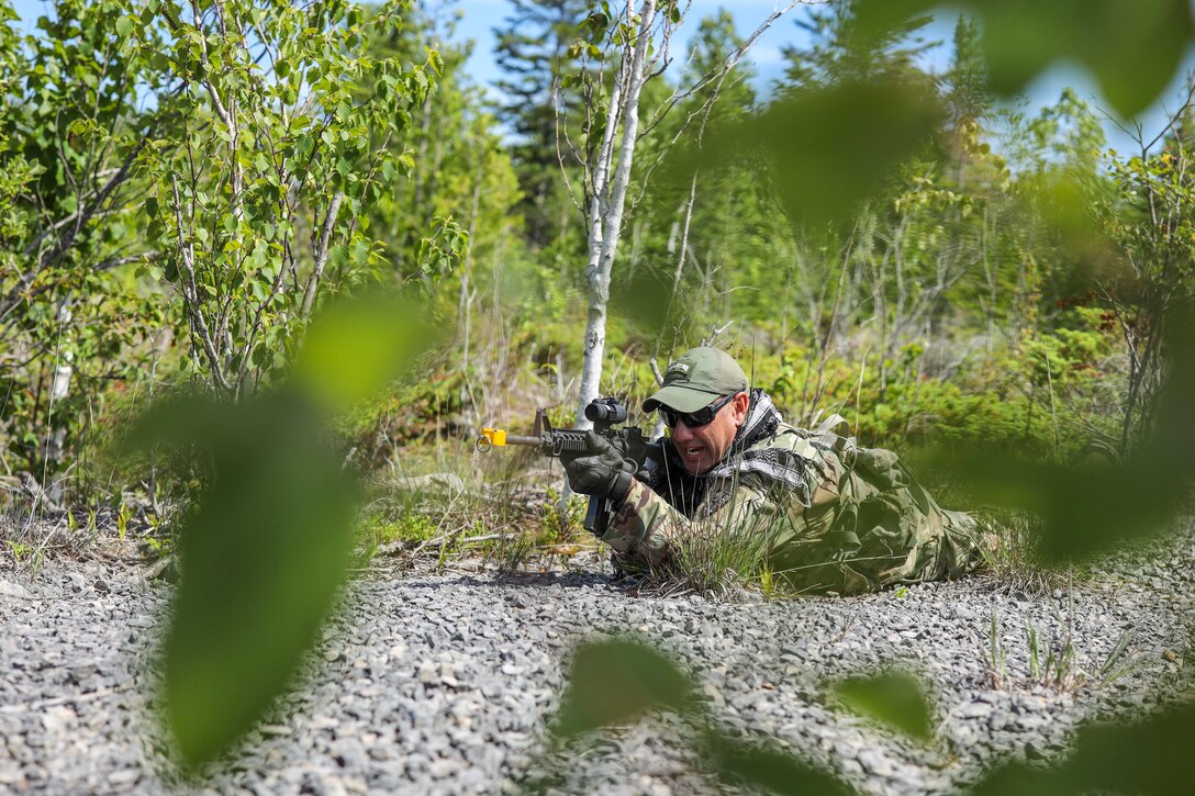 A soldier lies on the ground holding a weapon.