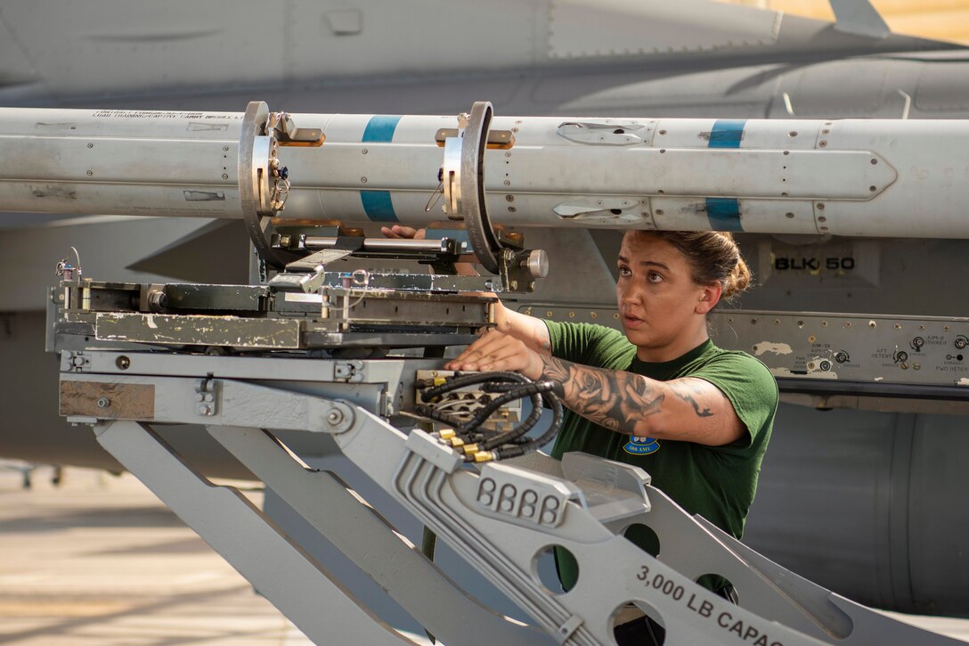 An airman loads a bomb onto an aircraft.