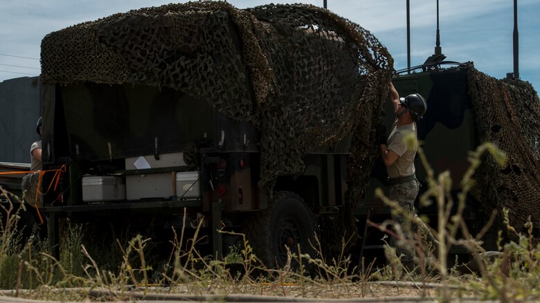 Senior Airman Jordan Jones, 726th Air Control Squadron radio frequency (RF) transmission systems technician, throws a camouflage tarp over a radio unit (RU) July 16, 2019, at Mountain Home Air Force Base, Idaho. Jones worked countless hours with his team to set up RUs and Tropo Satellite Support Radio (TSSRs) for Hardrock exercise 19-2. (U.S. Air Force photo by Senior Airman JaNae Capuno)