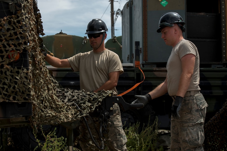 Senior Airman Jordan Jones and Senior Airman Paul Sexner, 726th Air Control Squadron radio frequency (RF) transmission systems technicians, secure a camouflage tarp over a radio unit (RU) July 16, 2019, at Mountain Home Air Force Base, Idaho. Jones worked countless hours with his team to set up RUs and Tropo Satellite Support Radio (TSSRs) for Hardrock exercise 19-2. (U.S. Air Force photo by Senior Airman JaNae Capuno)