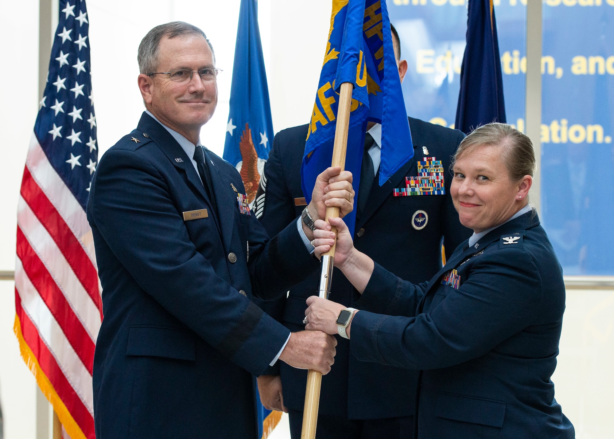 Brig. Gen. James Dienst, 711th Human Performance Wing commander, passes the U.S. Air Force School of Aerospace Medicine flag to Col. Theresa Goodman in a Change of Command ceremony July 19 to symbolize the change of command. (U.S. Air Force photo/Wesley Farnsworth)