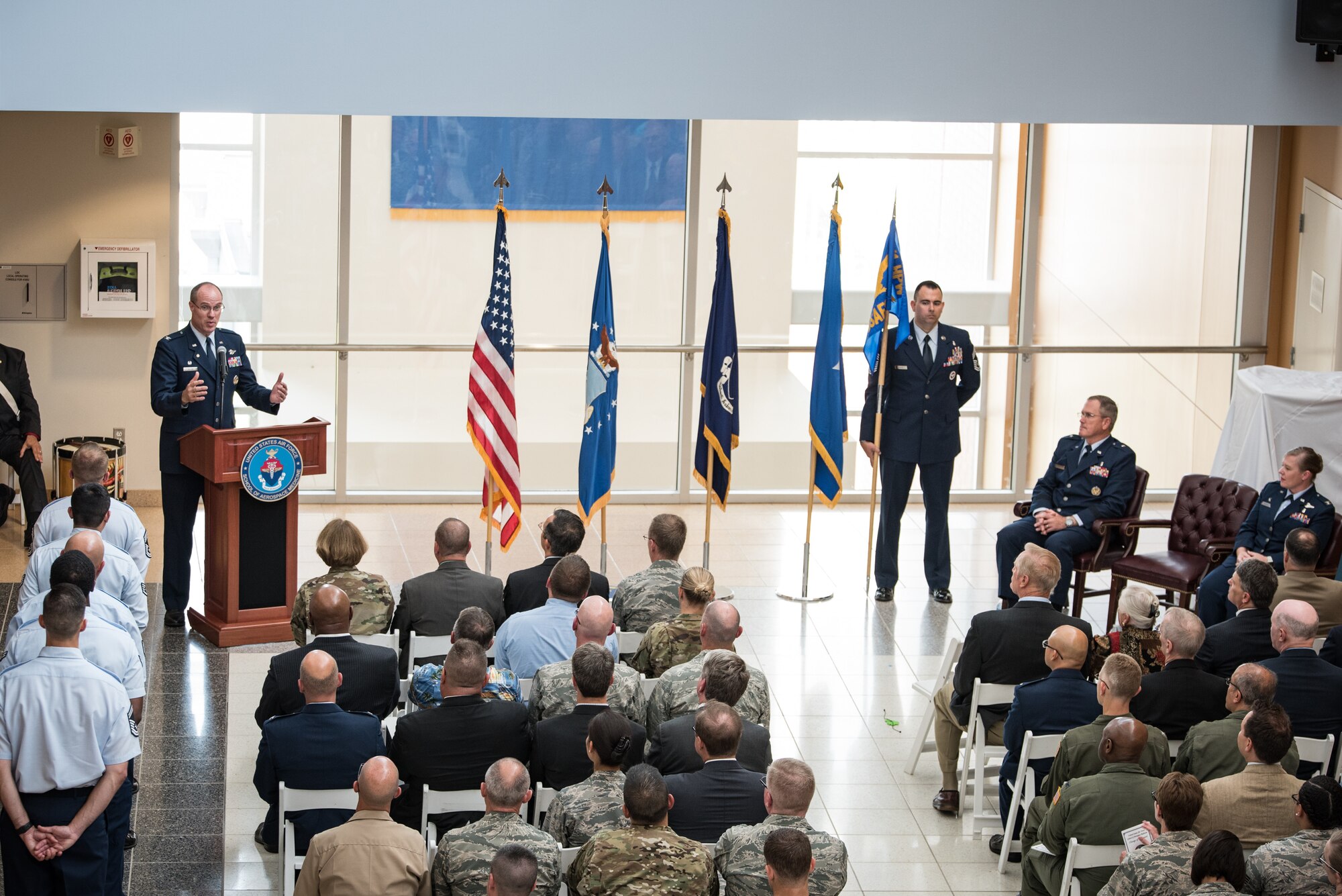 Col. (Ret.) Alden Hilton speaks to the crowd at the U.S. Air Force School of Aerospace Medicine Change of Command ceremony July 19 in the atrium of the schoolhouse. (U.S. Air Force photo/Richard Eldridge)