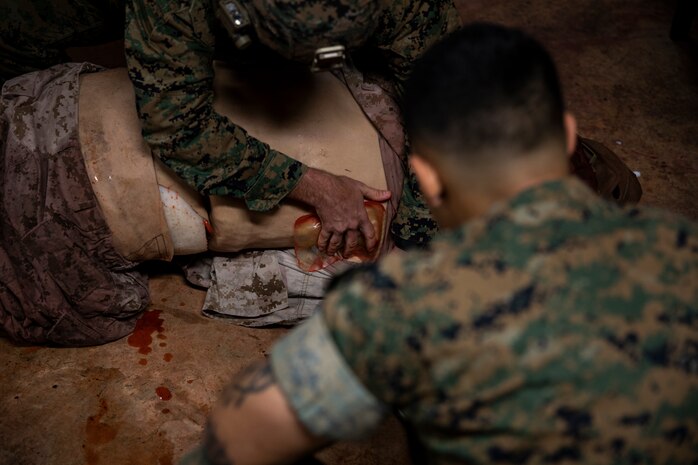 U.S. Marine Corps Maj. Zach Worth performs tactical field care while Hospital Corpsman 3rd Class Nicholas Berra Martinez assesses his performance at the end of a Tactical Combat Casualty Care course on Camp Hansen, Okinawa, Japan, July 11, 2019. The Medical Simulation Training Center trains Marines, throughout III Marine Expeditionary Force, in Combat Life Saving, TCCC and other field medical courses with the mission of eliminating preventable deaths on the battlefield. Worth, a native of The Dalles, Oregon, is an MV-22 Osprey pilot with Marine Aviation Group 36, 1st Marine Aircraft Wing. Berra Martinez, a native of Brooklyn, New York, is an instructor with the MSTC. (U.S. Marine Corps photo by Cpl. Jamin M. Powell)