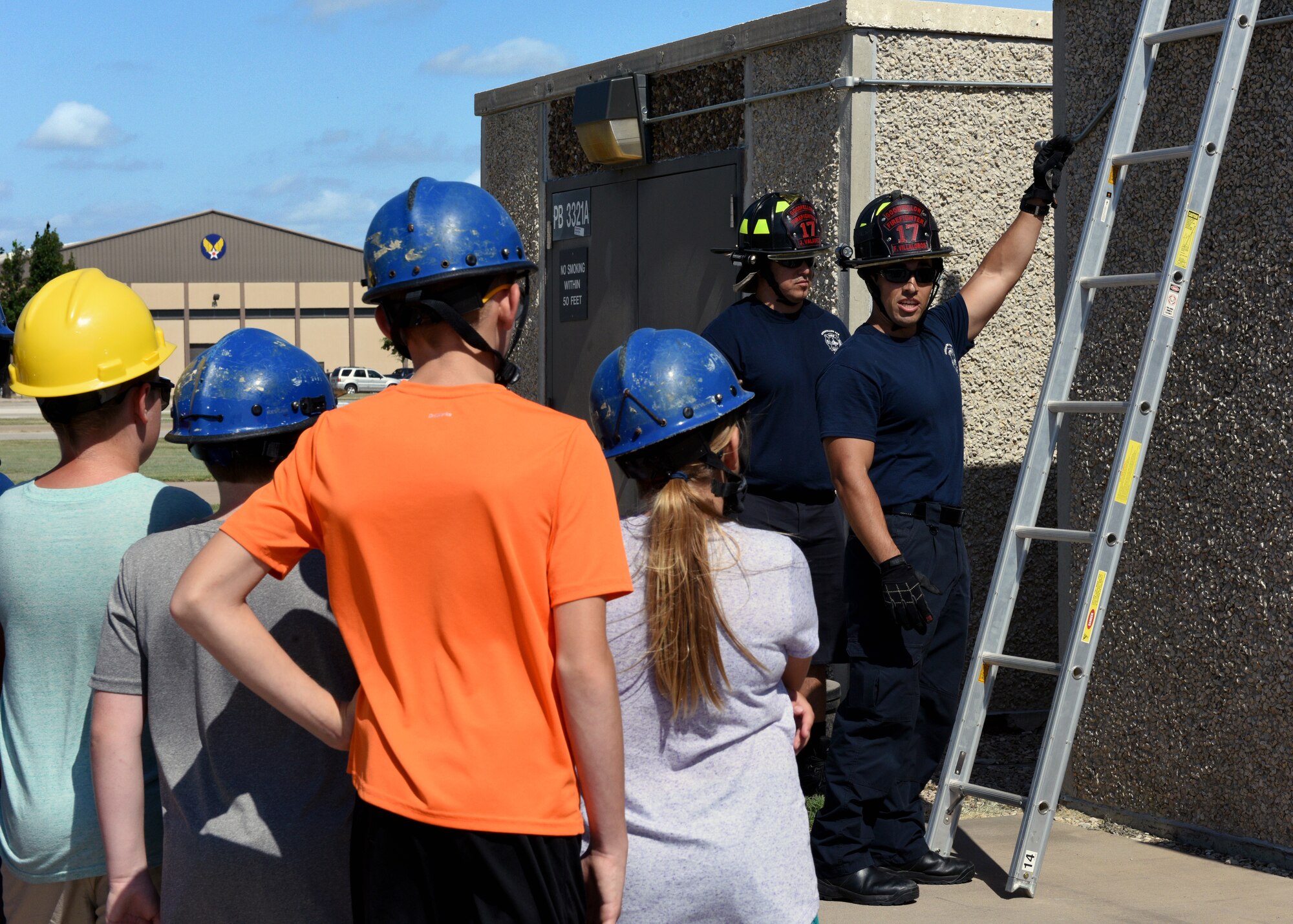 17th Civil Engineering Squadron Firefighters, Trevor Gardner and Frank Villalobos, show the junior firefighters proper ladder operations at the Goodfellow Air Force Base Fire Department on Goodfellow Air Force Base, Texas, July 18, 2019. The children watched a demonstration of ladder safety before ascending and descending in order to put what they learned into action. (U.S. Air Force photo by Airman 1st Class Robyn Hunsinger/Released)