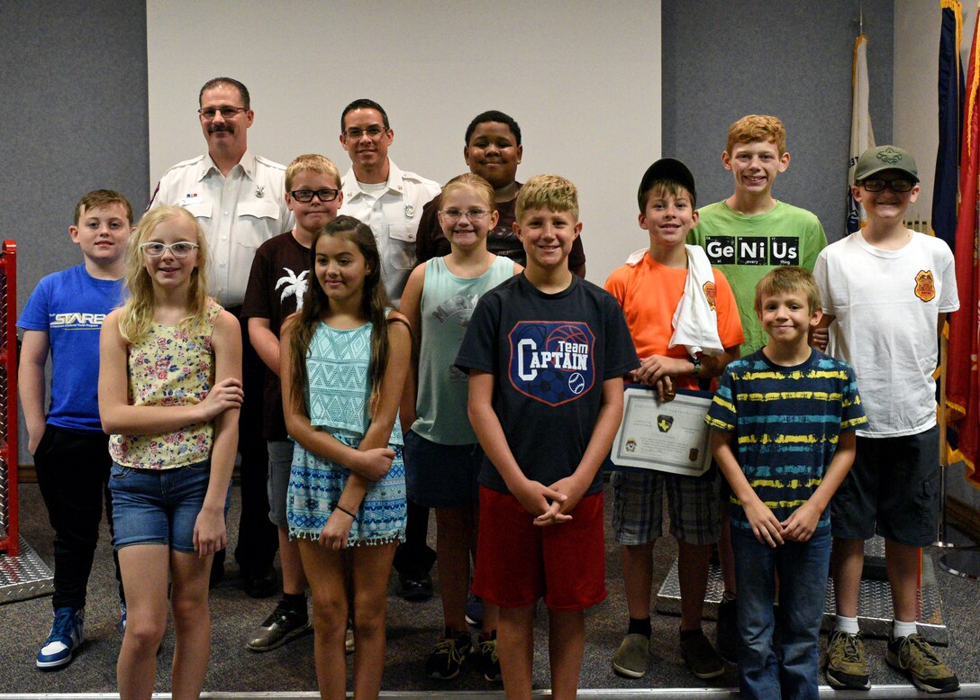 Junior firefighters and 17th Civil Engineering Squadron firefighters stand for a photos at the Louis F. Garland Department of Defense Fire Academy on Goodfellow Air Force Base, Texas, July 19, 2019. A graduation ceremony concluded the annual junior firefighter camp with a presentation of training certificates, a slideshow covering their week and refreshments. (U.S. Air Force photo by Airman 1st Class Robyn Hunsinger/Released)
