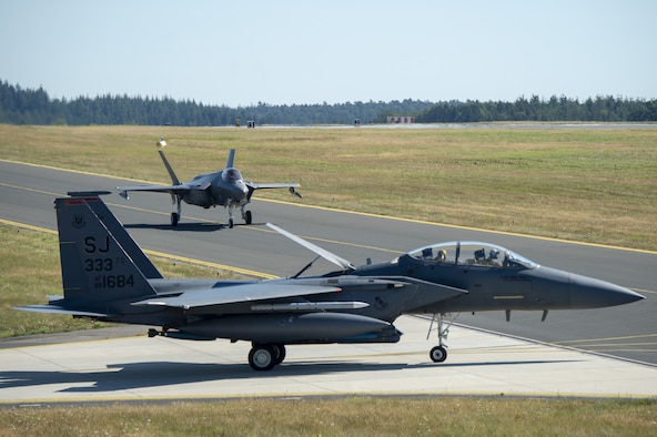 A U.S. Air Force F-35A Lighting II, assigned to the 421st Fighter Squadron, Hill Air Force Base, Utah, and a U.S. Air Force F-15E Strike Eagle, assigned to the 4th Fighter Wing, Seymour Johnson Air Force Base, North Carolina, taxis on the flightline during Operation Rapid Forge at Spangdahlem Air Base, Germany, July 23, 2019. Rapid Forge aircraft are forward deploying to bases in the territory of NATO allies in order to enhance readiness and improve interoperability. (U.S. Air Force photo by Airman 1st Class Branden Rae)