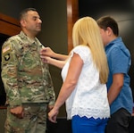Newly promoted Master Sgt. Erivan Rodriguez’s wife, Norma Molina, and son, Yerevan, place his new rank on his uniform during a promotion ceremony.