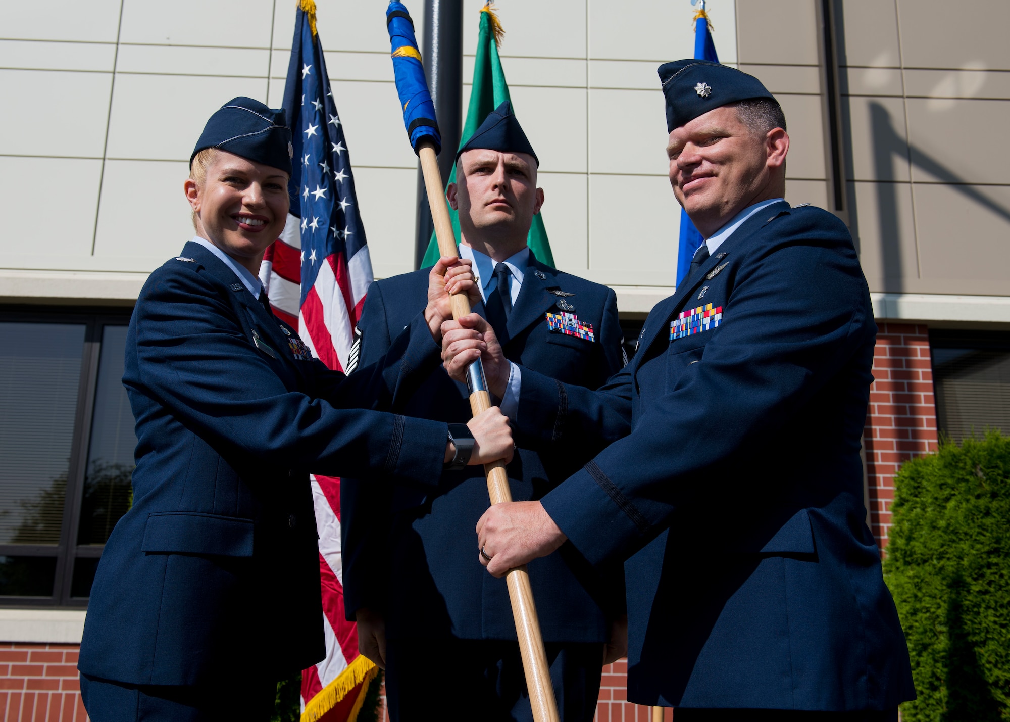 U.S. Air Force Lt. Col. Heather Nelson, 92nd Medical Group commander, passes the new 92nd Operational Medical Readiness Squadron guidon to Lt. Col. Daniel Hatcher, 92nd OMRS commander, during a re-designation ceremony at Fairchild Air Force Base, Washington, July 19, 2019. The purpose of the medical re-designation is to better focus resources to promote readiness and ensure retirees and beneficiaries their health care benefits. (U.S. Air Force photo by Airman 1st Class Lawrence Sena)