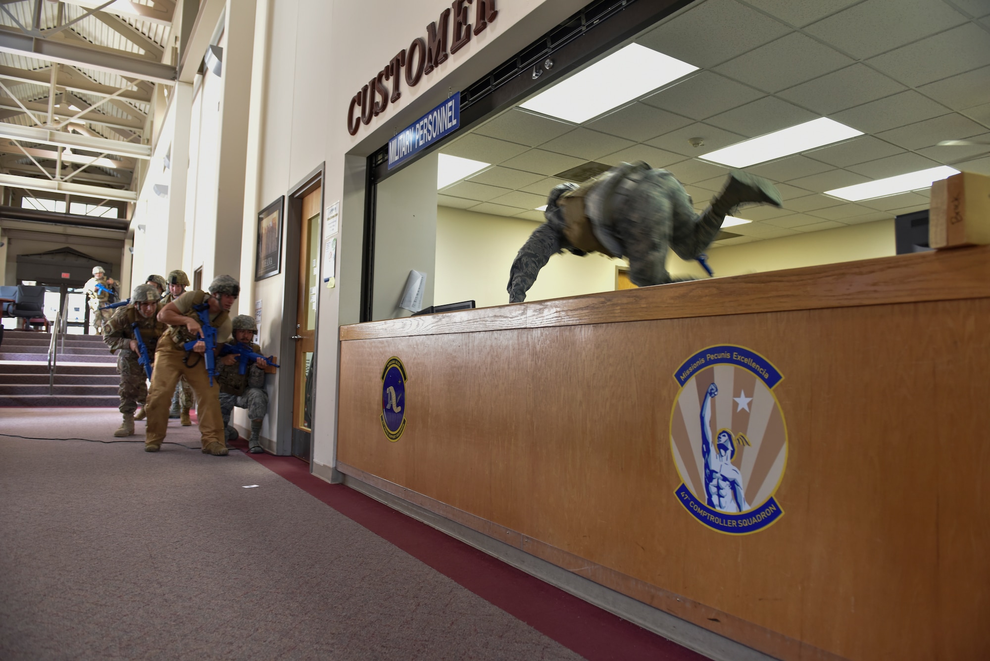 Airman 1st Class Lukenus San Boh vaults a customer service counter to clear the way for his teammates during an active shooter training exercise at Laughlin Air Force Base, Texas, July 22, 2019. After devising a plan, the team jumped into action to recover the simulated hostages being kept by a simulated barricaded suspect. For nearly two hours the defenders practiced negotiation, room clearing and recovery techniques. (U.S. Air Force photo by Staff Sgt. Benjamin N. Valmoja)
