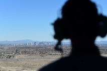 Airman 1st Class William Rosado, 432nd Wing/432nd Air Expeditionary Wing photojournalist, looks out at the Las Vegas skyline from a 66th Rescue Squadron HH-60G Pave Hawk, July 15, 2019. Aircrew with the 66th RS conducted training exercises on the Nevada Test and Training Range and integrated with MQ-9 Reaper aircrew to document the Reaper in flight. (U.S. Air Force photo by Senior Airman Haley Stevens)