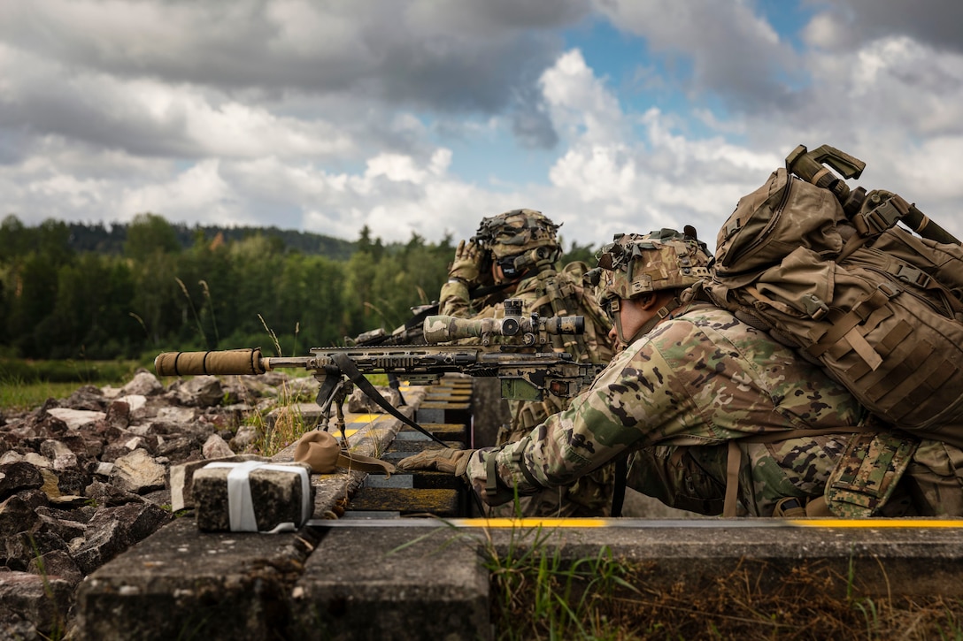 A soldier leans over a weapon.