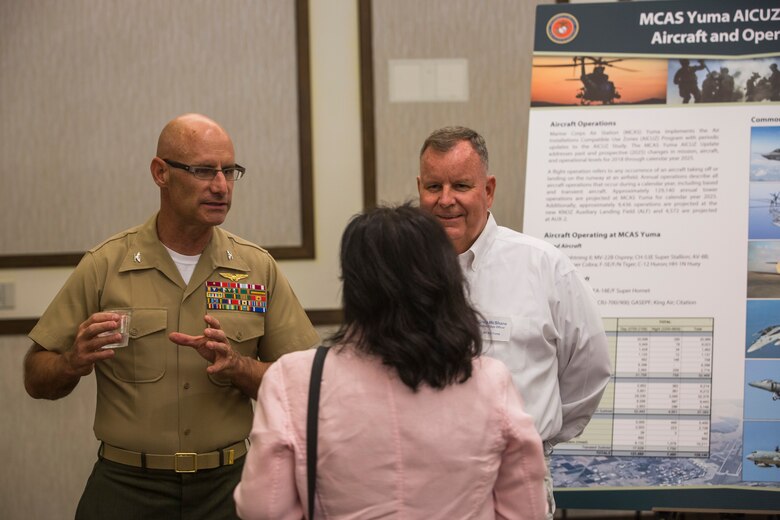 Col. David A. Suggs, the commanding officer of Marine Corps Air Station (MCAS) Yuma, and several base personnel interact with members of the local Yuma community during the Air Installations Compatible Use Zones (AICUZ) Open House at the Pivot Point Conference Center in Yuma, Ariz., July 17, 2019. The Department of Defense established the AICUZ program to assist local governments and communities in identifying and planning for compatible land use and development in the vecinity of military air installations. The primary functions of the AICUZ study is to present noise contours and accident potential zones for an airfield. (U.S. Marine Corps photo by Sgt. Isaac D. Martinez)