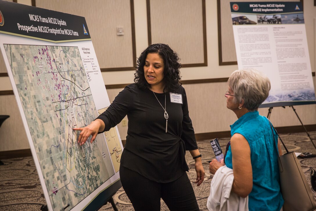 Col. David A. Suggs, the commanding officer of Marine Corps Air Station (MCAS) Yuma, and several base personnel interact with members of the local Yuma community during the Air Installations Compatible Use Zones (AICUZ) Open House at the Pivot Point Conference Center in Yuma, Ariz., July 17, 2019. The Department of Defense established the AICUZ program to assist local governments and communities in identifying and planning for compatible land use and development in the vecinity of military air installations. The primary functions of the AICUZ study is to present noise contours and accident potential zones for an airfield. (U.S. Marine Corps photo by Sgt. Isaac D. Martinez)