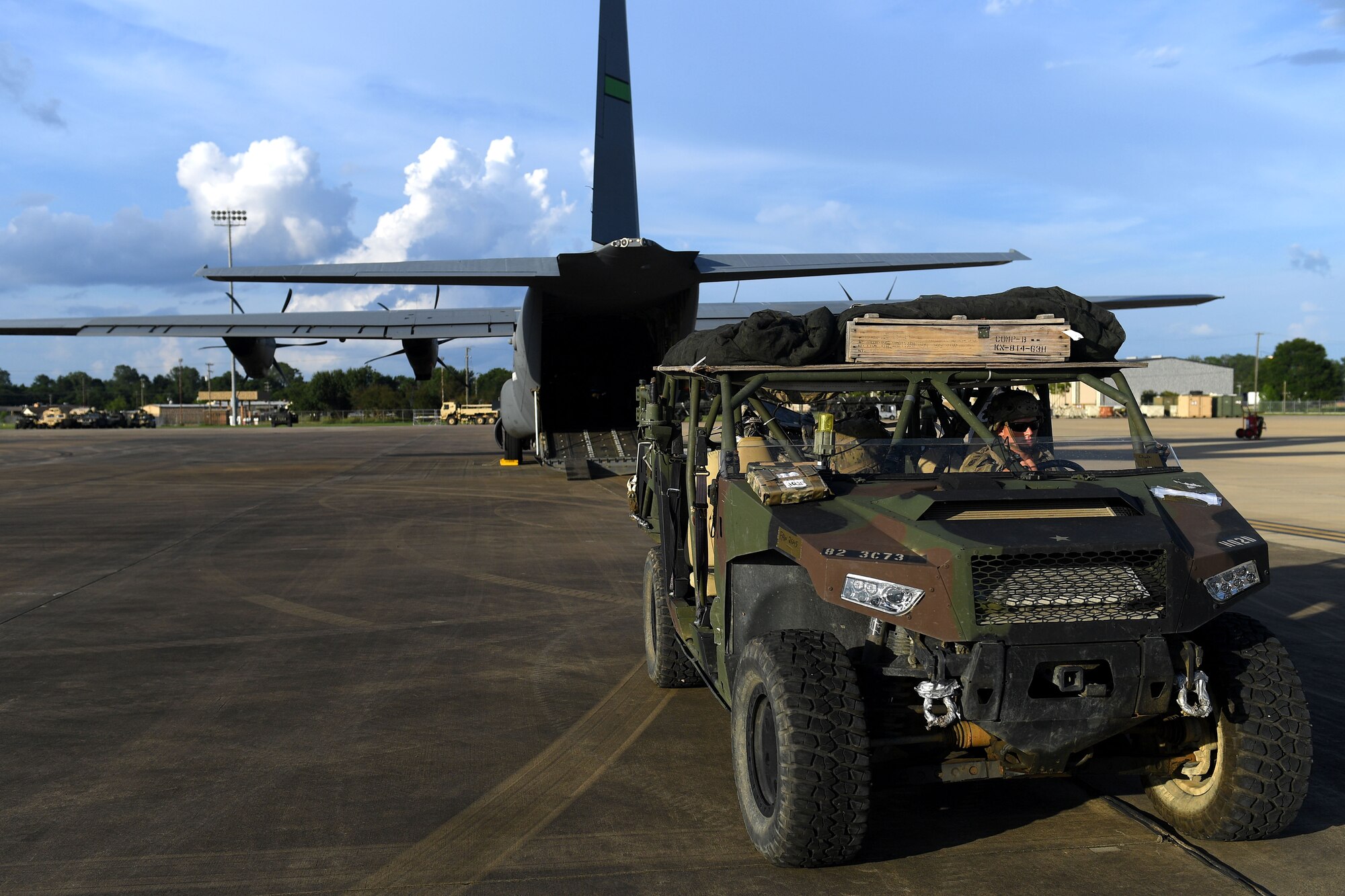 A humvee is in front of a C-130J.