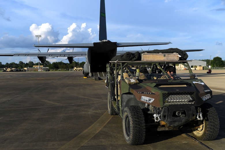 A humvee is in front of a C-130J.