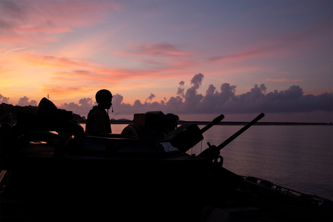 A Marine checks equipment in the sunset.