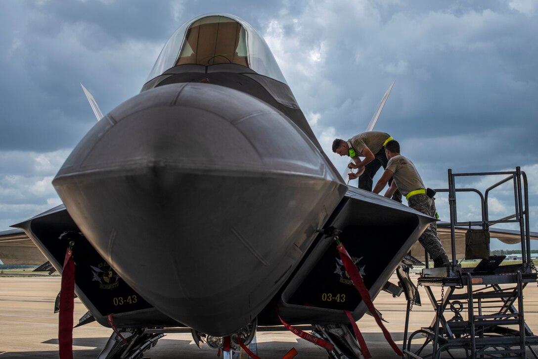 Two airmen work on an aircraft.