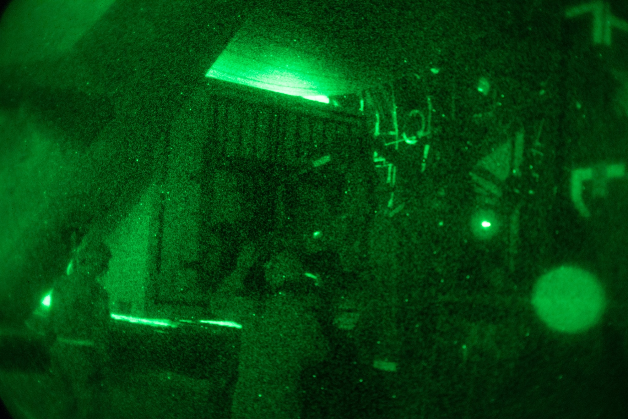 Airmen assist with loading cargo to a C-130 using night vision equipment.