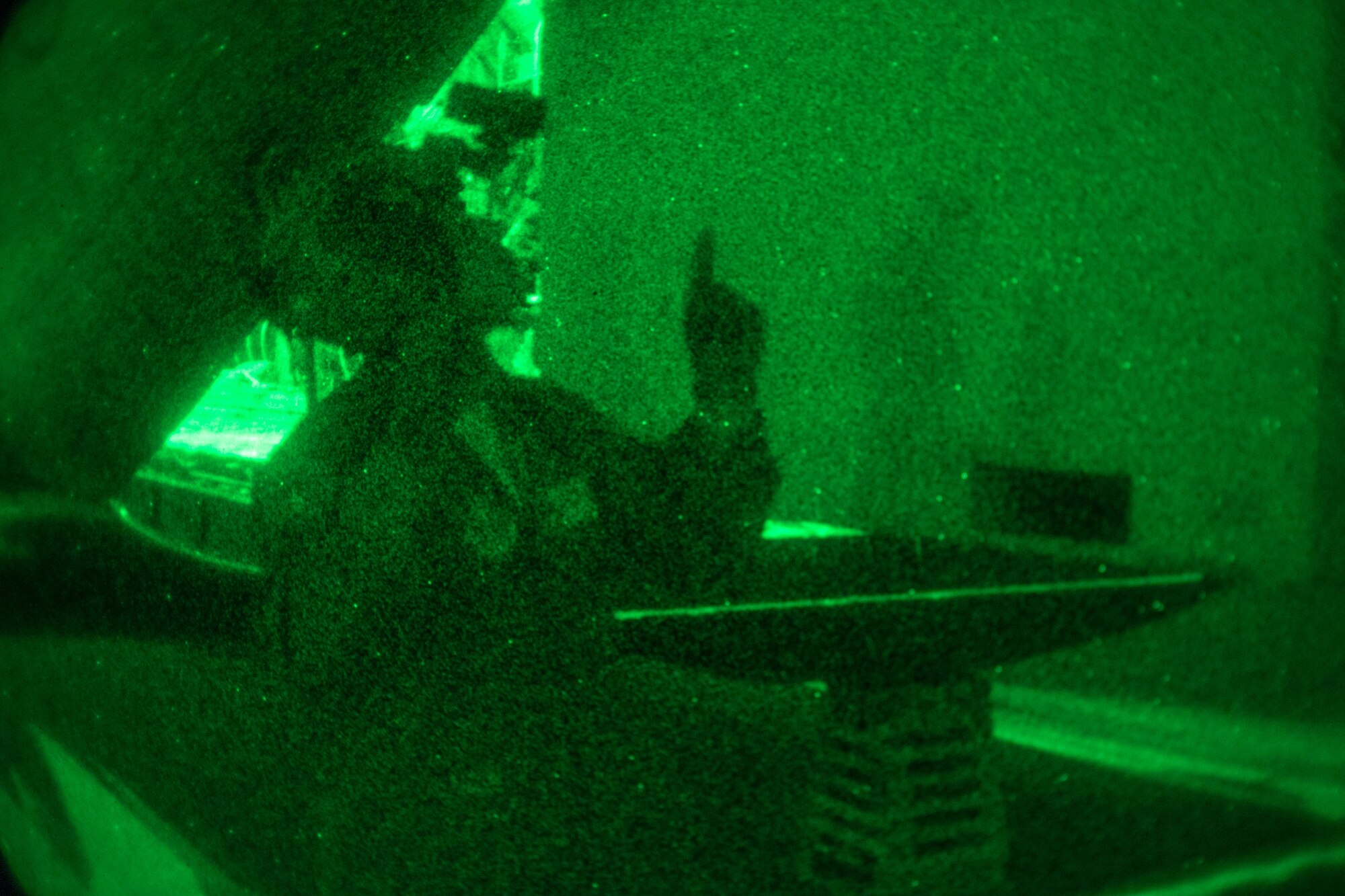 An Airman points up to indicate cargo should be lifted higher during loading to a C-130.